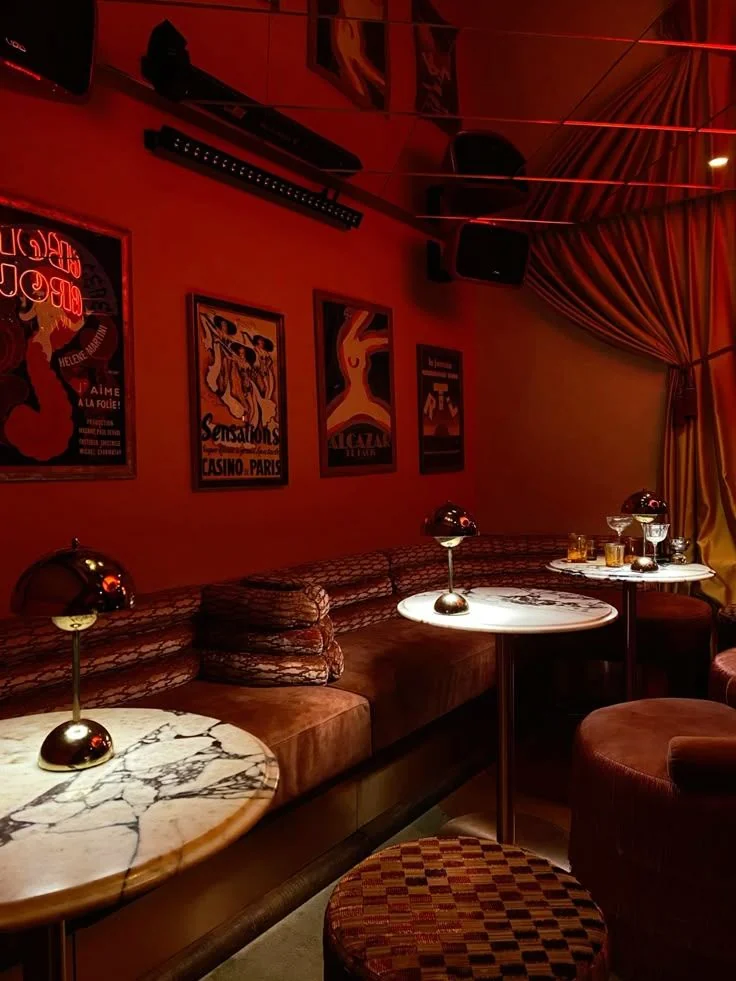 Interior de un bar rojo con sofás de terciopelo y mesas de mármol